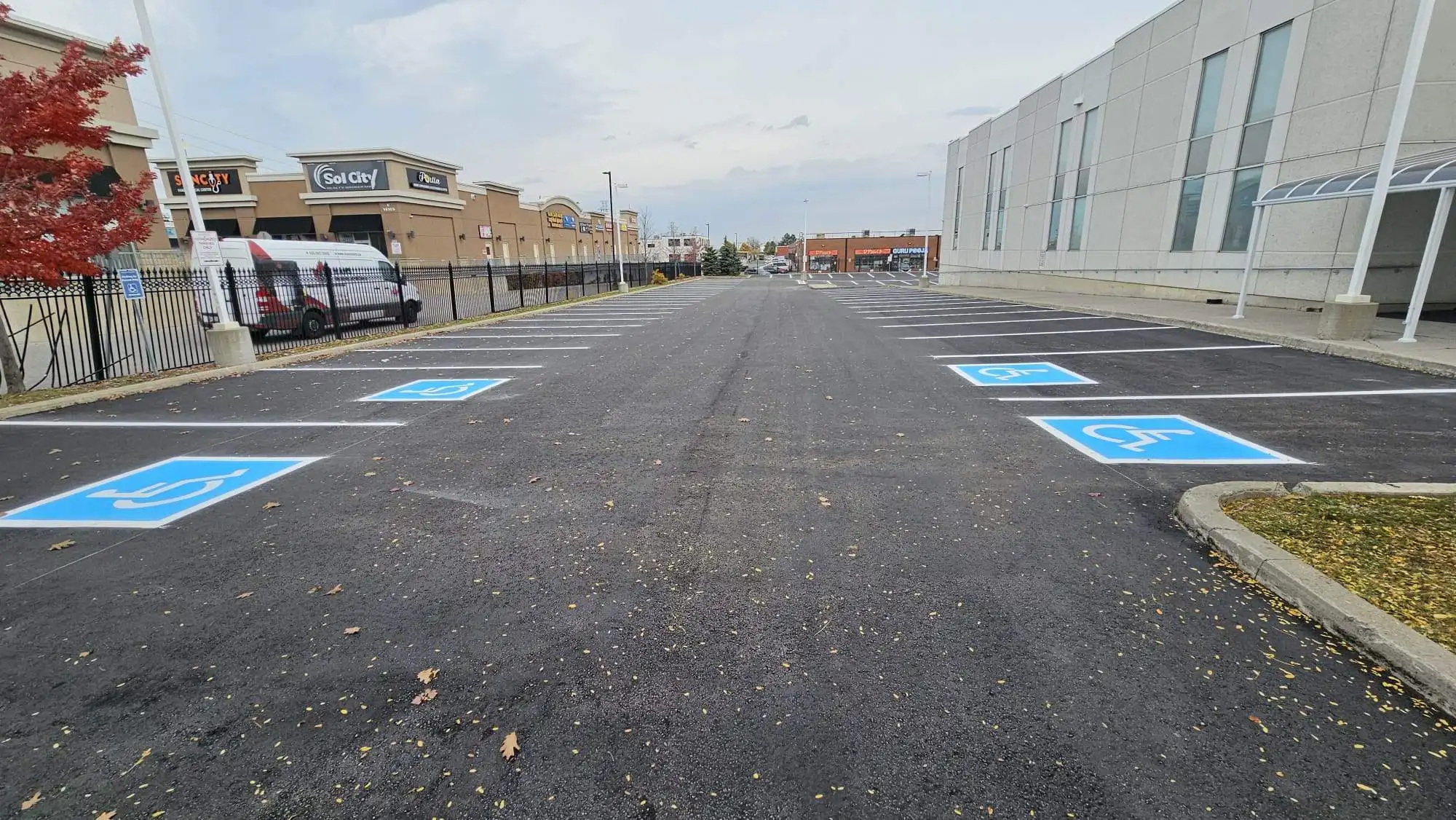 Freshly paved commercial parking lot in front of retail buildings in Ontario, featuring clearly marked accessible parking spaces and crisp line striping.