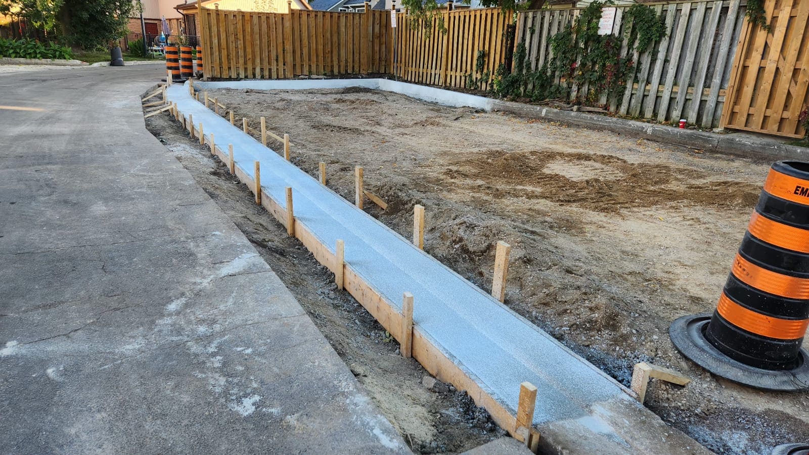 Freshly poured concrete sidewalk and curb installation by Empire Paving at a residential project site in Pickering, Ontario.