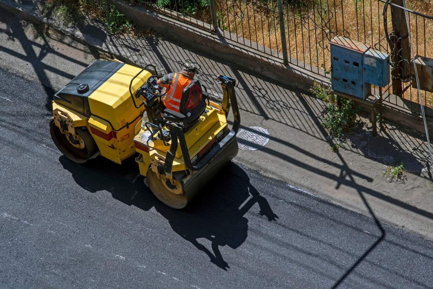 Aerial view of a yellow truck laying asphalt