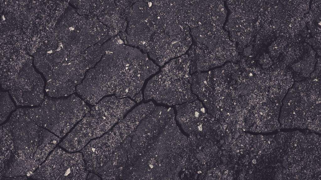 Top-down close-up of severely cracked and deteriorated asphalt pavement surface needing fall maintenance and repair by Empire Paving.
